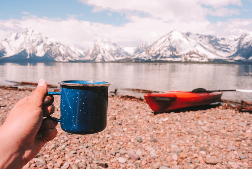 A Coffee Mug and a Kayak with a view of a Lake and Mountains
